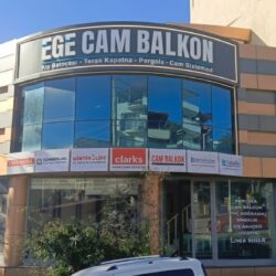 İzmir'de modern bir villanın bahçesine uygulanan, antrasit gri alüminyum pergola sistemi; altındaki konforlu oturma grubu, ateş çukuru ve Ege'nin simgesi zeytin ağaçlarıyla bütünleşmiş, motorlu ve LED aydınlatmalı raylı tente tasarımı.